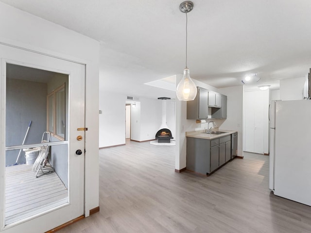 26 Arthur Ave SE Unit 304, Minneapolis, MN 55414 - kitchen featuring freestanding refrigerator, gray cabinetry, a sink, light wood-style floors, and light countertops