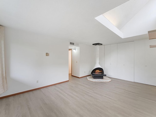 26 Arthur Ave SE Unit 304, Minneapolis, MN 55414 - unfurnished living room featuring a wood stove, light wood finished floors, and baseboards
