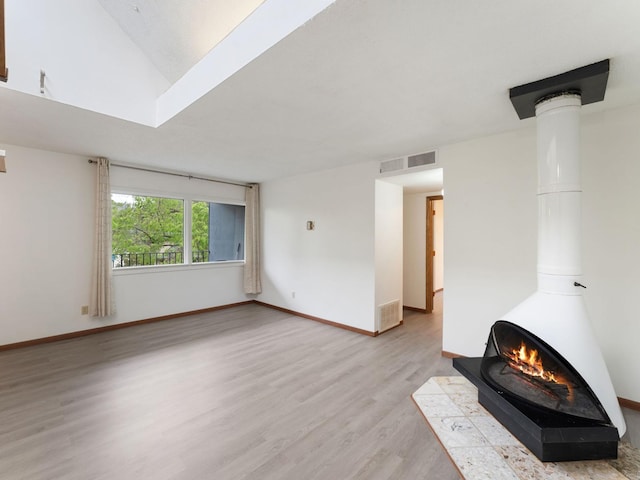 26 Arthur Ave SE Unit 304, Minneapolis, MN 55414 - unfurnished living room featuring light wood finished floors, a wood stove, and baseboards