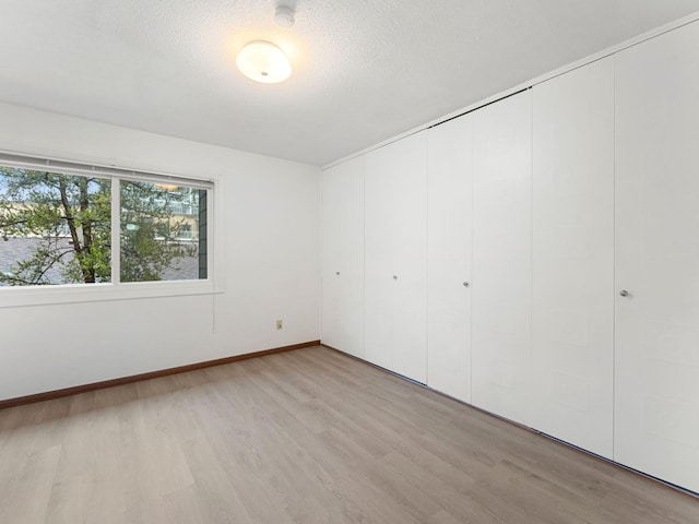 26 Arthur Ave SE Unit 304, Minneapolis, MN 55414 - unfurnished bedroom featuring light wood-type flooring, baseboards, a closet, and a textured ceiling