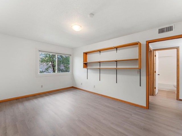 26 Arthur Ave SE Unit 304, Minneapolis, MN 55414 - unfurnished room with light wood-type flooring, baseboards, a smoke detector, and a textured ceiling