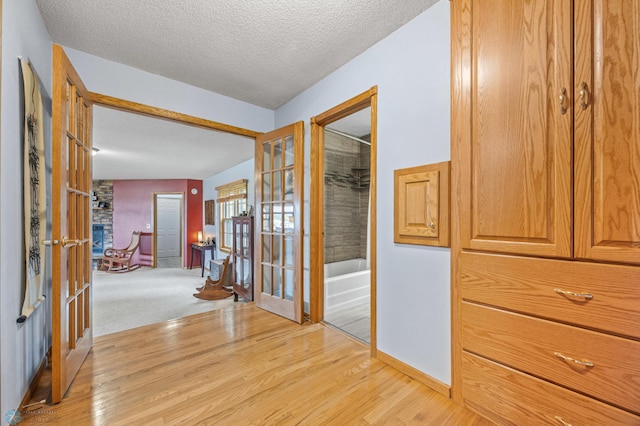 20482 28th Ave N, Cromwell Twp, MN 56549 - hall with french doors, a textured ceiling, light wood finished floors, and baseboards