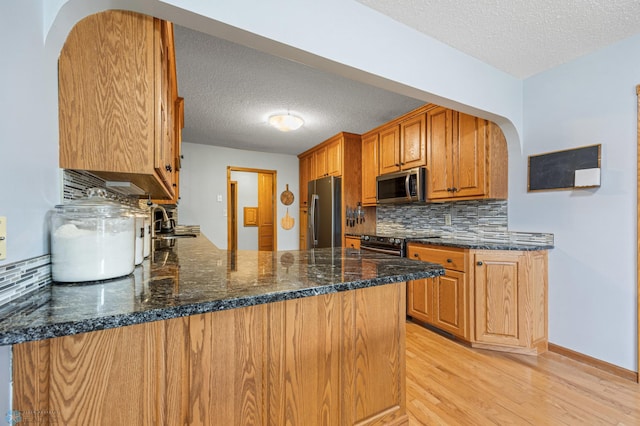 20482 28th Ave N, Cromwell Twp, MN 56549 - kitchen featuring stainless steel appliances, a textured ceiling, arched walkways, a sink, and light wood-type flooring
