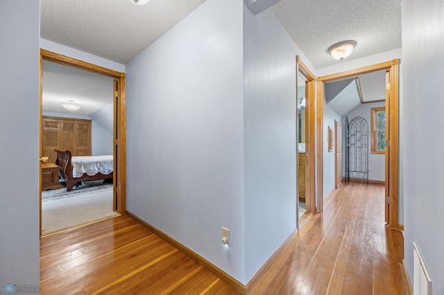 20482 28th Ave N, Cromwell Twp, MN 56549 - corridor featuring a textured ceiling, wood-type flooring, baseboards, and vaulted ceiling