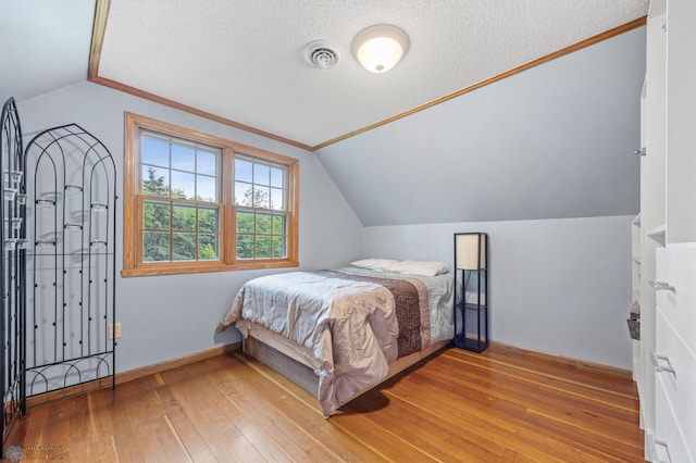 20482 28th Ave N, Cromwell Twp, MN 56549 - bedroom featuring lofted ceiling, light wood-style flooring, a textured ceiling, and baseboards