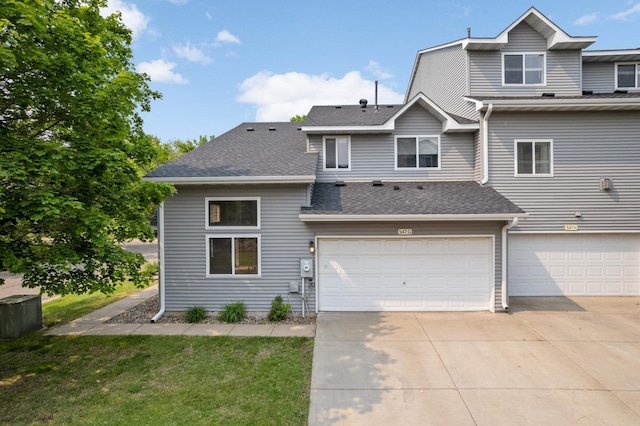 547 Woodduck Dr Unit G, Woodbury, MN 55125 - view of front of house with concrete driveway, an attached garage, roof with shingles, and a front lawn