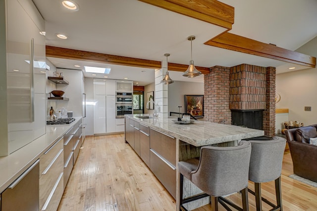 120 Eastbank Ct N, North Hudson, WI 54016 - kitchen with modern cabinets, beamed ceiling, a sink, light wood-style flooring, and a kitchen breakfast bar