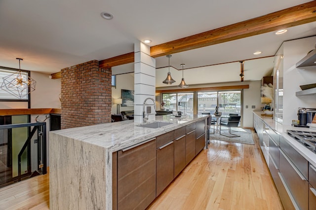 120 Eastbank Ct N, North Hudson, WI 54016 - kitchen featuring a sink, beam ceiling, light wood-style floors, light stone counters, and hanging light fixtures