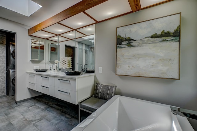 120 Eastbank Ct N, North Hudson, WI 54016 - bathroom featuring stacked washer / drying machine, vanity, a freestanding bath, a skylight, and recessed lighting