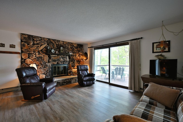 W2847 County Highway B, Madge Twp, WI 54870 - living room featuring a textured ceiling, wood finished floors, a baseboard radiator, and a stone fireplace