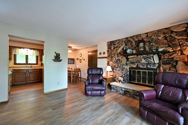 W2847 County Highway B, Madge Twp, WI 54870 - living room with wood finished floors, a textured ceiling, a fireplace, and baseboards