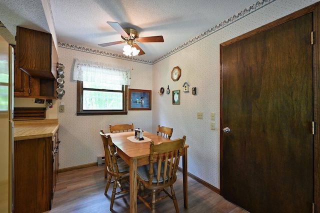 W2847 County Highway B, Madge Twp, WI 54870 - dining room featuring dark wood finished floors, ceiling fan, wallpapered walls, baseboards, and a textured ceiling