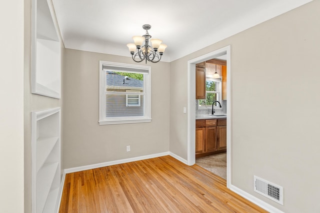 4342 Arthur St NE, Columbia Heights, MN 55421 - empty room with a sink, a chandelier, light wood-type flooring, and baseboards