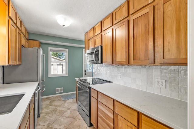 4342 Arthur St NE, Columbia Heights, MN 55421 - kitchen with appliances with stainless steel finishes, backsplash, baseboards, light countertops, and a textured ceiling