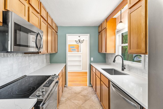 4342 Arthur St NE, Columbia Heights, MN 55421 - kitchen featuring stainless steel appliances, a sink, decorative backsplash, pendant lighting, and a textured ceiling