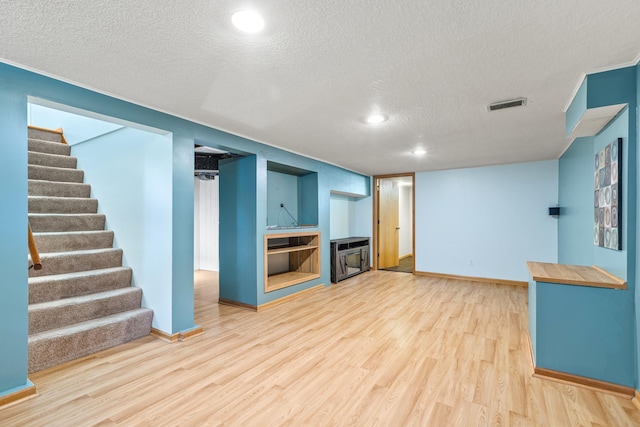 4342 Arthur St NE, Columbia Heights, MN 55421 - finished basement with light wood-style flooring, a textured ceiling, stairs, baseboards, and a fireplace