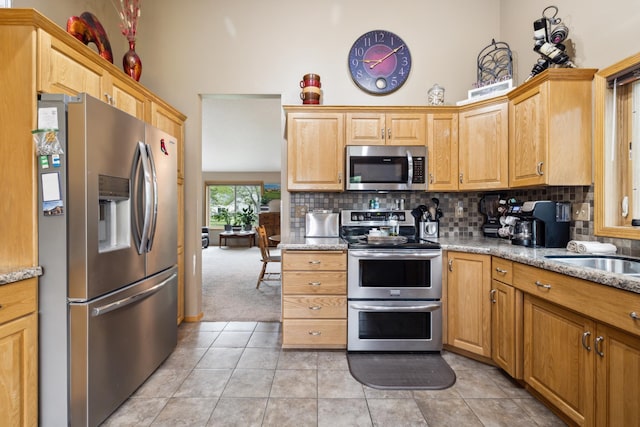 2031 Rose Creek Dr S, Fargo, ND 58104 - kitchen with appliances with stainless steel finishes, a towering ceiling, backsplash, light tile patterned floors, and a sink