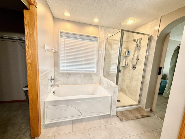 10809 Tyler Ct NE, Blaine, MN 55434 - full bathroom with a garden tub, a textured ceiling, a stall shower, tile patterned floors, and a walk in closet