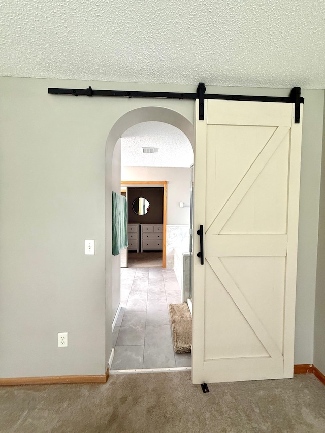10809 Tyler Ct NE, Blaine, MN 55434 - hallway with a textured ceiling, arched walkways, baseboards, carpet, and a barn door