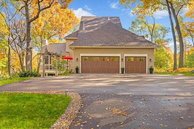 4266 Manor Court Rd, Minnetonka, MN 55345 - view of side of property featuring a chimney, stucco siding, asphalt driveway, roof with shingles, and an attached garage