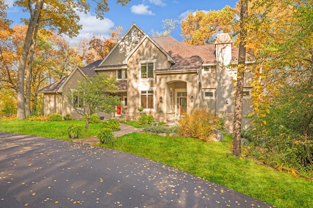 4266 Manor Court Rd, Minnetonka, MN 55345 - view of front facade with a front yard, stucco siding, a chimney, and stone siding