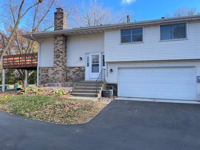 12232 Oak Leaf Cir, Burnsville, MN 55337 - bi-level home featuring a garage, asphalt driveway, a chimney, central AC unit, and a wooden deck