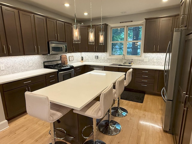 4312 France Ave S, Edina, MN 55410 - kitchen featuring appliances with stainless steel finishes, light wood finished floors, a kitchen breakfast bar, dark brown cabinetry, and recessed lighting