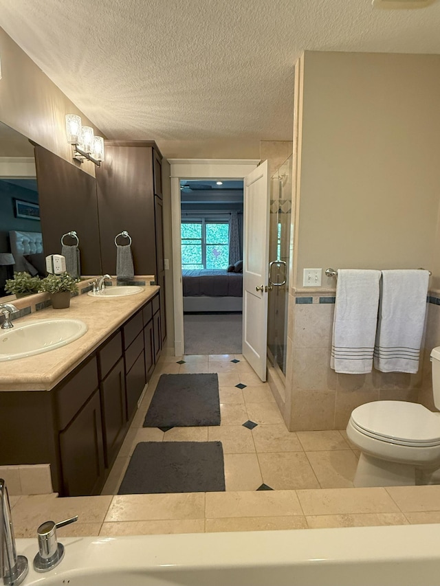 4312 France Ave S, Edina, MN 55410 - ensuite bathroom featuring toilet, double vanity, a textured ceiling, a shower stall, and tile patterned flooring