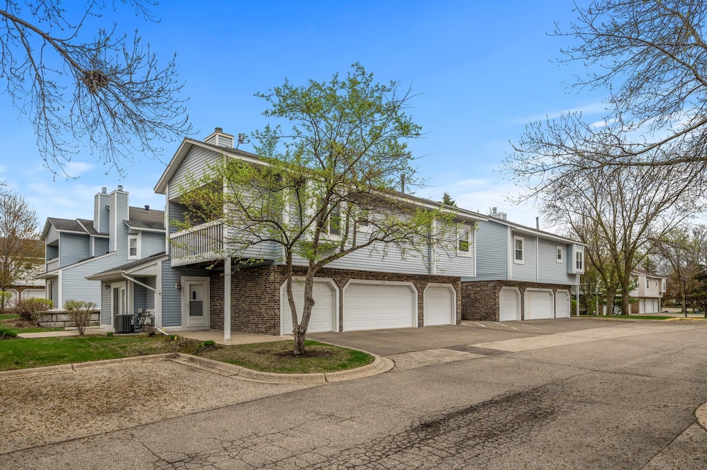 5345 Highpointe Ter, Bloomington, MN 55437 - view of front of property with a garage, a balcony, asphalt driveway, a chimney, and a residential view