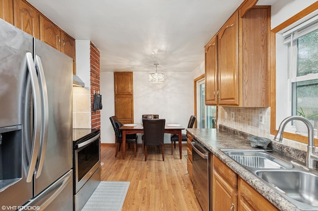 220 State St, Belle Plaine, MN 56011 - kitchen with appliances with stainless steel finishes, a sink, light wood finished floors, decorative backsplash, and brown cabinetry