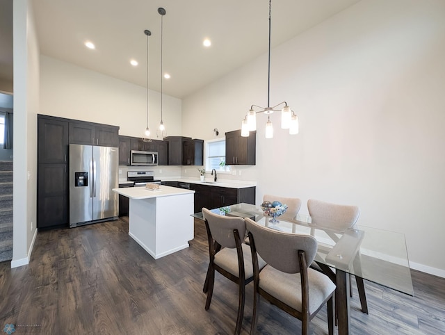 2715 11th St W, West Fargo, ND 58078 - kitchen with appliances with stainless steel finishes, a towering ceiling, a center island, light countertops, and dark wood-style flooring