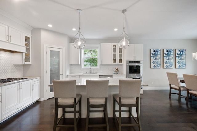 12601 Ridgemount Ave W, Minnetonka, MN 55305 - kitchen with appliances with stainless steel finishes, a sink, tasteful backsplash, a kitchen bar, and dark wood-style flooring