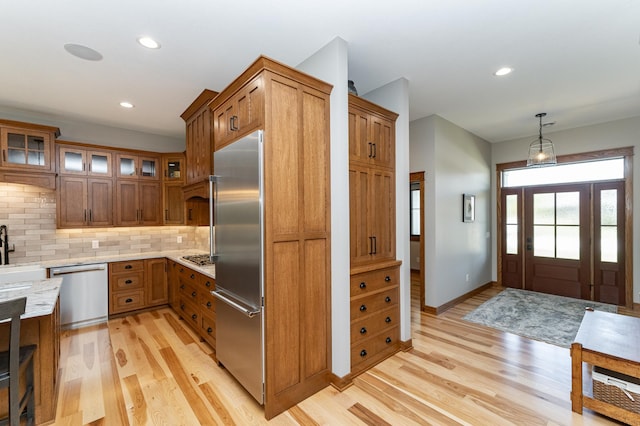 918 Hidden Meadow Ln, Lake City, MN 55041 - kitchen with stainless steel appliances, brown cabinets, light wood finished floors, decorative backsplash, and glass insert cabinets