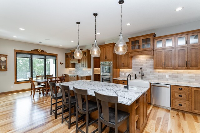 918 Hidden Meadow Ln, Lake City, MN 55041 - kitchen with appliances with stainless steel finishes, brown cabinets, light wood-style floors, an island with sink, and recessed lighting