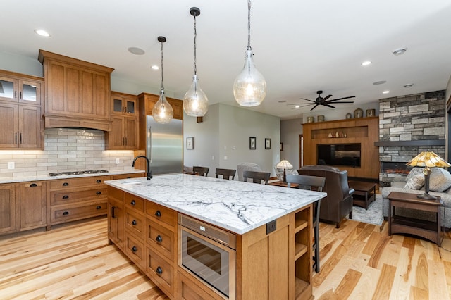 918 Hidden Meadow Ln, Lake City, MN 55041 - kitchen featuring built in appliances, a sink, a fireplace, decorative light fixtures, and brown cabinetry