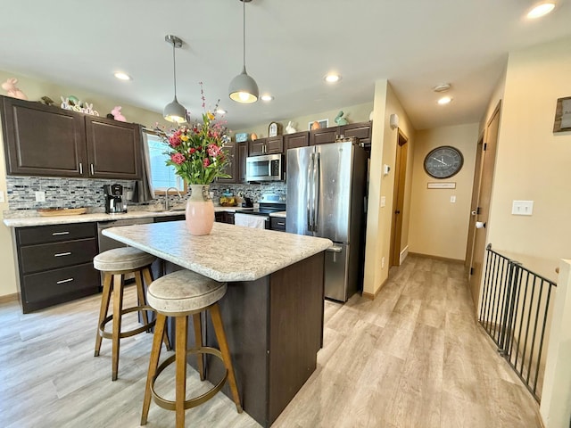 2014 Nelson Dr, Thief River Falls, MN 56701 - kitchen featuring stainless steel appliances, dark brown cabinets, light wood-style flooring, decorative backsplash, and light countertops
