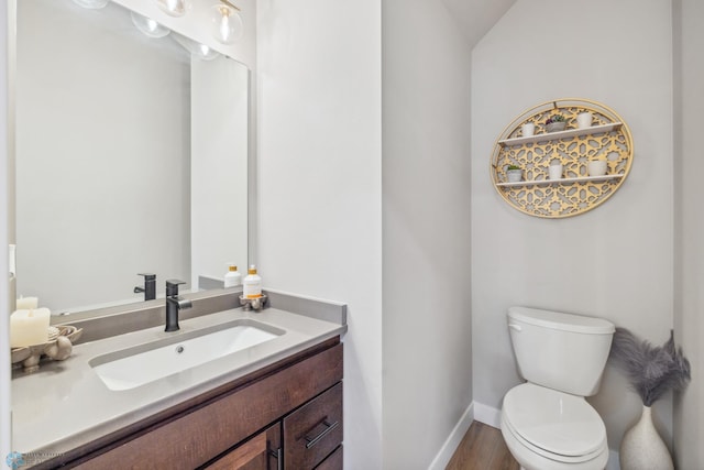 5837 41st St S, Fargo, ND 58104 - half bath featuring toilet, vanity, baseboards, and wood finished floors