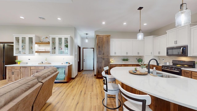 807 Whitetail Ln, Detroit Lakes, MN 56501 - kitchen featuring stainless steel gas stove, wine cooler, a sink, light wood-style floors, and a breakfast bar