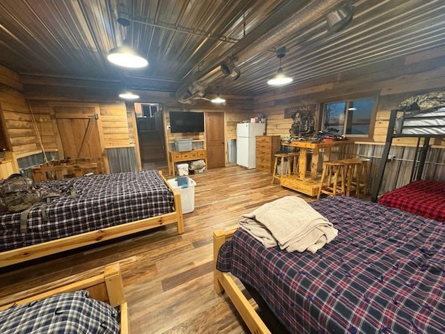 46824 Foss Rd, Osage, MN 56570 - bedroom with wood finished floors, wooden walls, and freestanding refrigerator