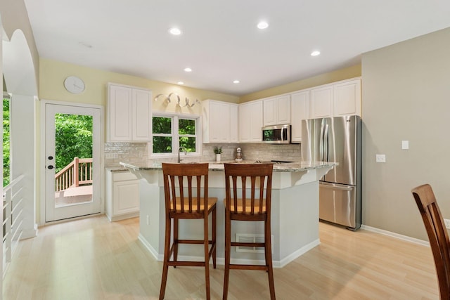 6609 Red Birch Ct, Lino Lakes, MN 55014 - kitchen featuring stainless steel appliances, tasteful backsplash, light wood finished floors, a kitchen breakfast bar, and recessed lighting