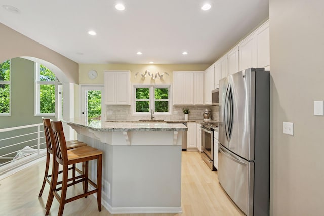 6609 Red Birch Ct, Lino Lakes, MN 55014 - kitchen featuring appliances with stainless steel finishes, a kitchen breakfast bar, a sink, white cabinets, and decorative backsplash