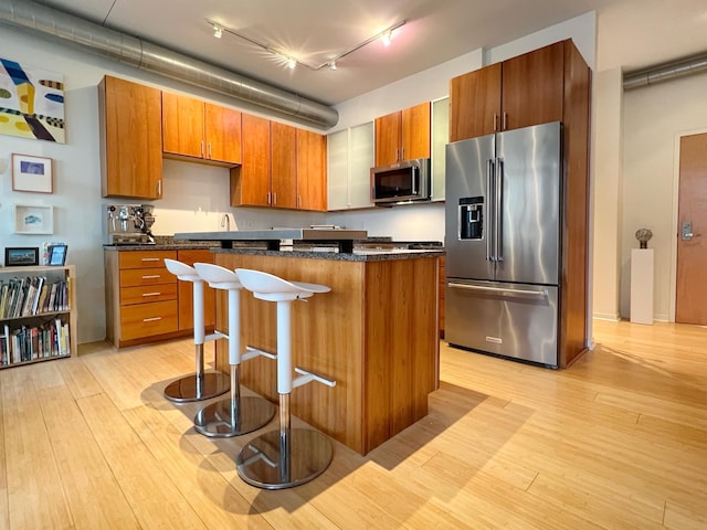 2840 Bryant Ave S Unit E303, Minneapolis, MN 55408 - kitchen featuring appliances with stainless steel finishes, light wood-style flooring, track lighting, a kitchen island, and a breakfast bar