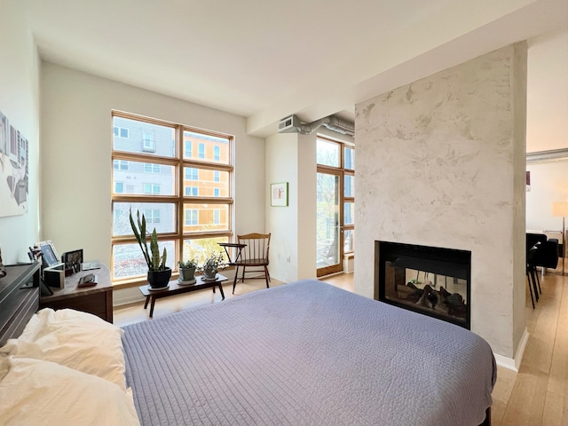 2840 Bryant Ave S Unit E303, Minneapolis, MN 55408 - bedroom with light wood-type flooring, a multi sided fireplace, and baseboards
