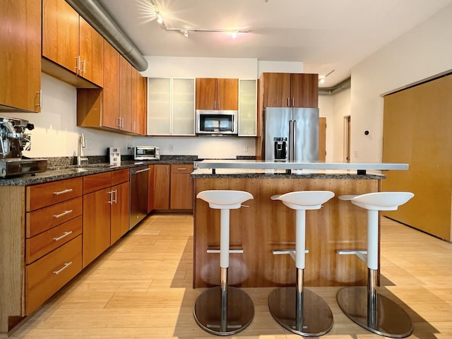2840 Bryant Ave S Unit E303, Minneapolis, MN 55408 - kitchen with appliances with stainless steel finishes, a kitchen breakfast bar, light wood-style flooring, a kitchen island, and track lighting