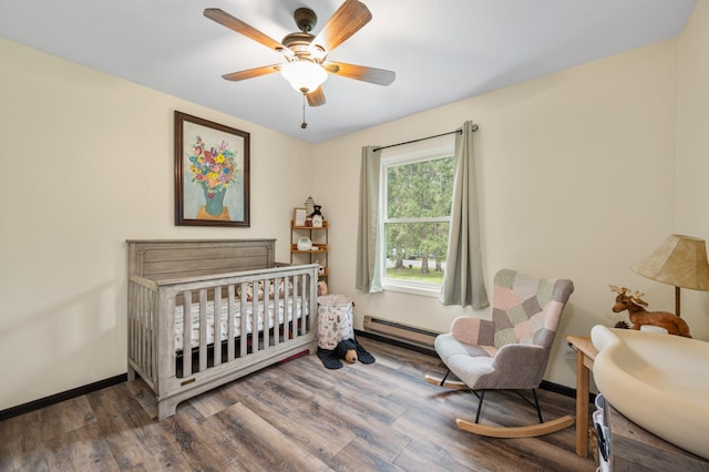 3108 4th Ave, Grand Rapids, MN 55744 - bedroom with a baseboard radiator, wood finished floors, a ceiling fan, a crib, and baseboards