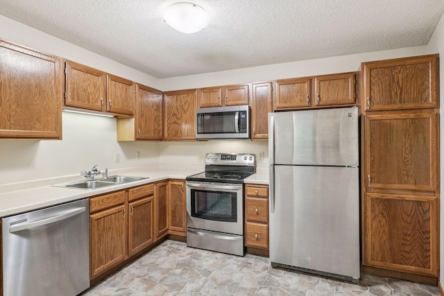 10726 Toledo Ct, Bloomington, MN 55437 - kitchen with stainless steel appliances, a sink, brown cabinets, a textured ceiling, and light countertops