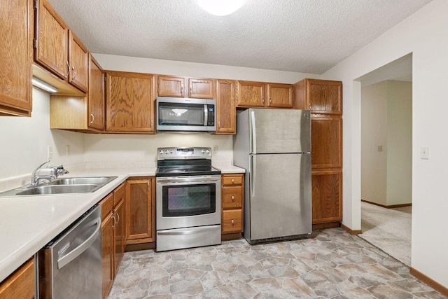10726 Toledo Ct, Bloomington, MN 55437 - kitchen with stainless steel appliances, a sink, a textured ceiling, light countertops, and brown cabinetry
