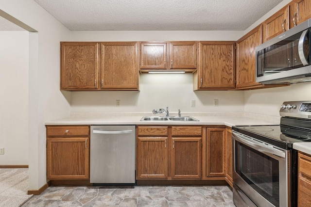10726 Toledo Ct, Bloomington, MN 55437 - kitchen featuring appliances with stainless steel finishes, a sink, light countertops, a textured ceiling, and brown cabinets