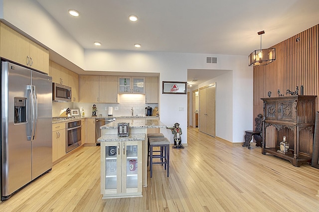 740 Portland Ave Unit 1005, Minneapolis, MN 55415 - kitchen with stainless steel appliances, a kitchen breakfast bar, a chandelier, light wood-style floors, and decorative backsplash