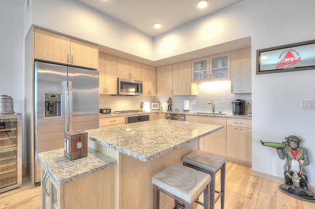 740 Portland Ave Unit 1005, Minneapolis, MN 55415 - kitchen with stainless steel appliances, light brown cabinetry, beverage cooler, a kitchen breakfast bar, and recessed lighting